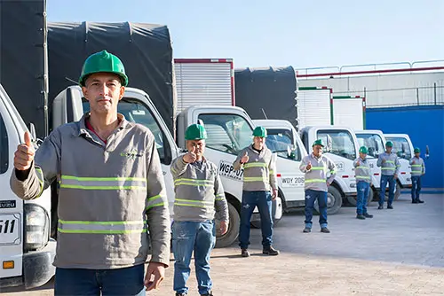 personal de ecopositiva en frente de flota de camiones de reciclaje